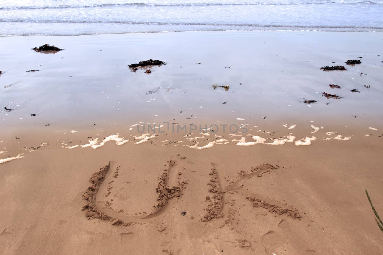 uk inscribed on the beach with ocean waves in the background