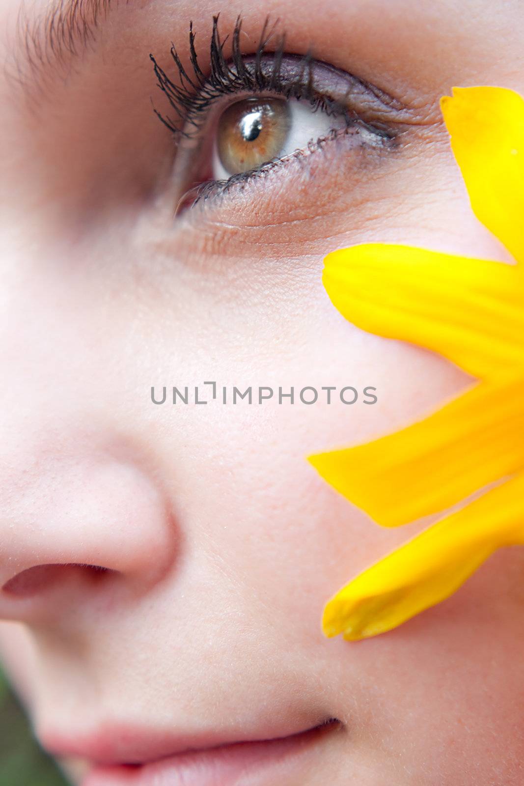 Close up of the face of a woman that is wearing a black eyed susan wildflower in her hair.  Shallow depth of field.