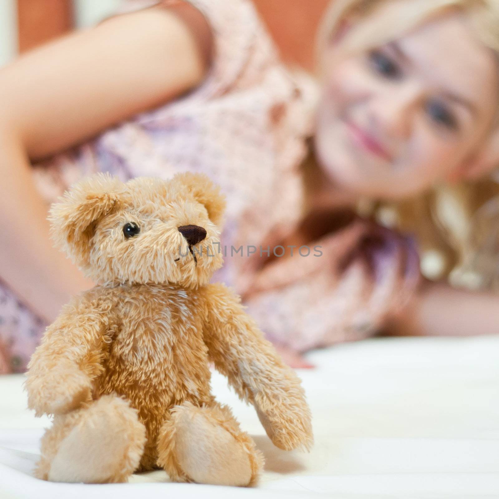 Beautiful young girl with bear toy in bed