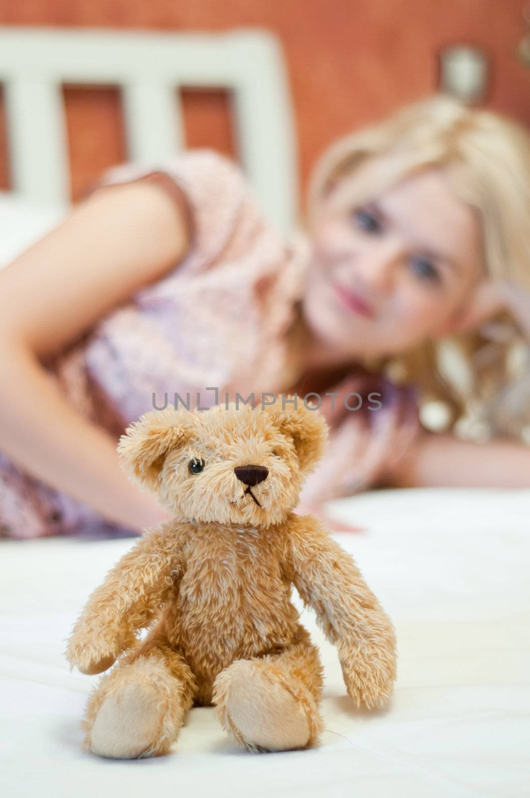 Beautiful young girl with bear toy in bed