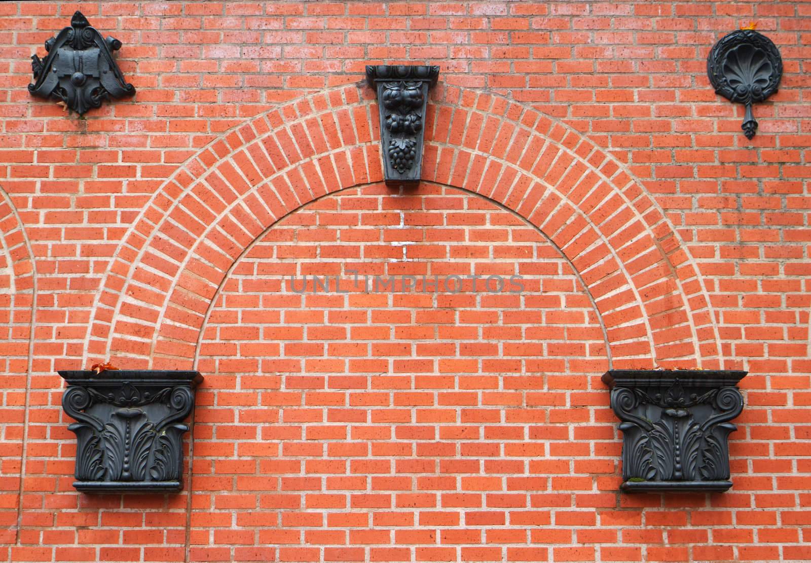 Red brick wall with arch features and black iron ornamentation