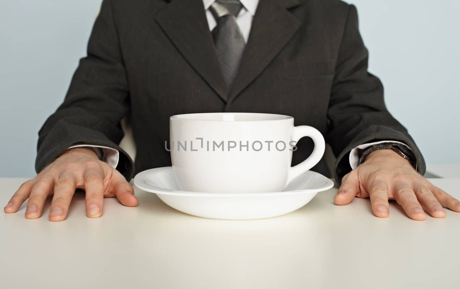 Huge cup of coffee on table near businessman by pzaxe