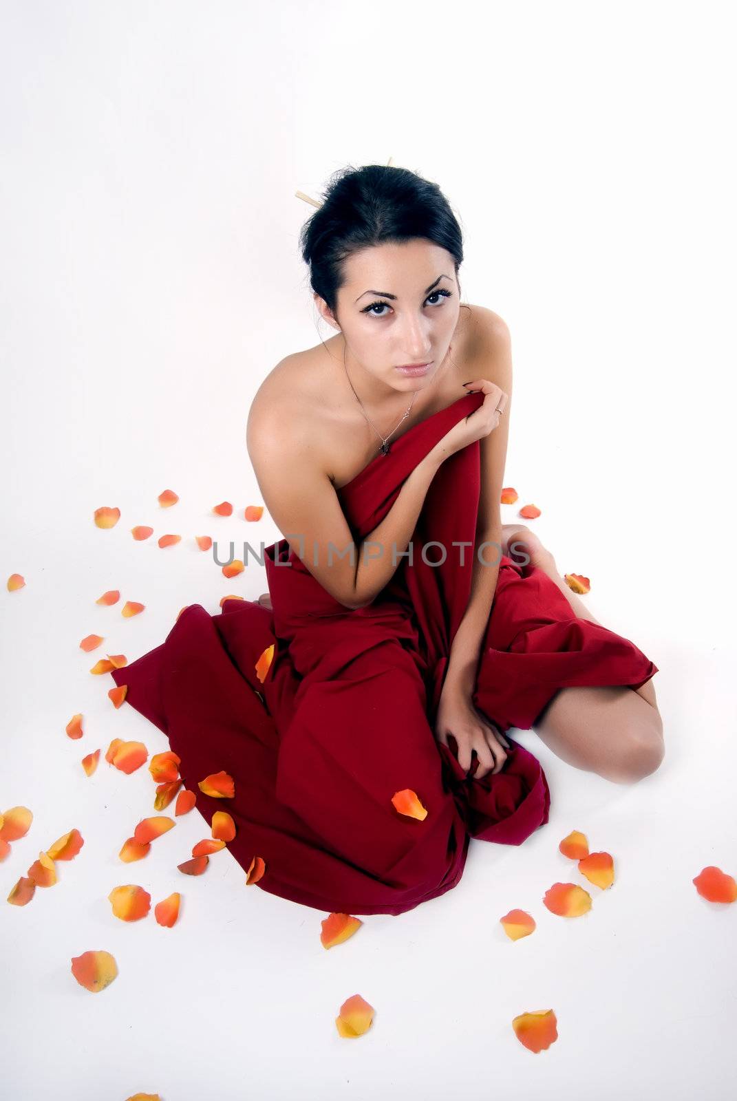 Portrait of a young seductive Asian brunette in falling leaves of roses