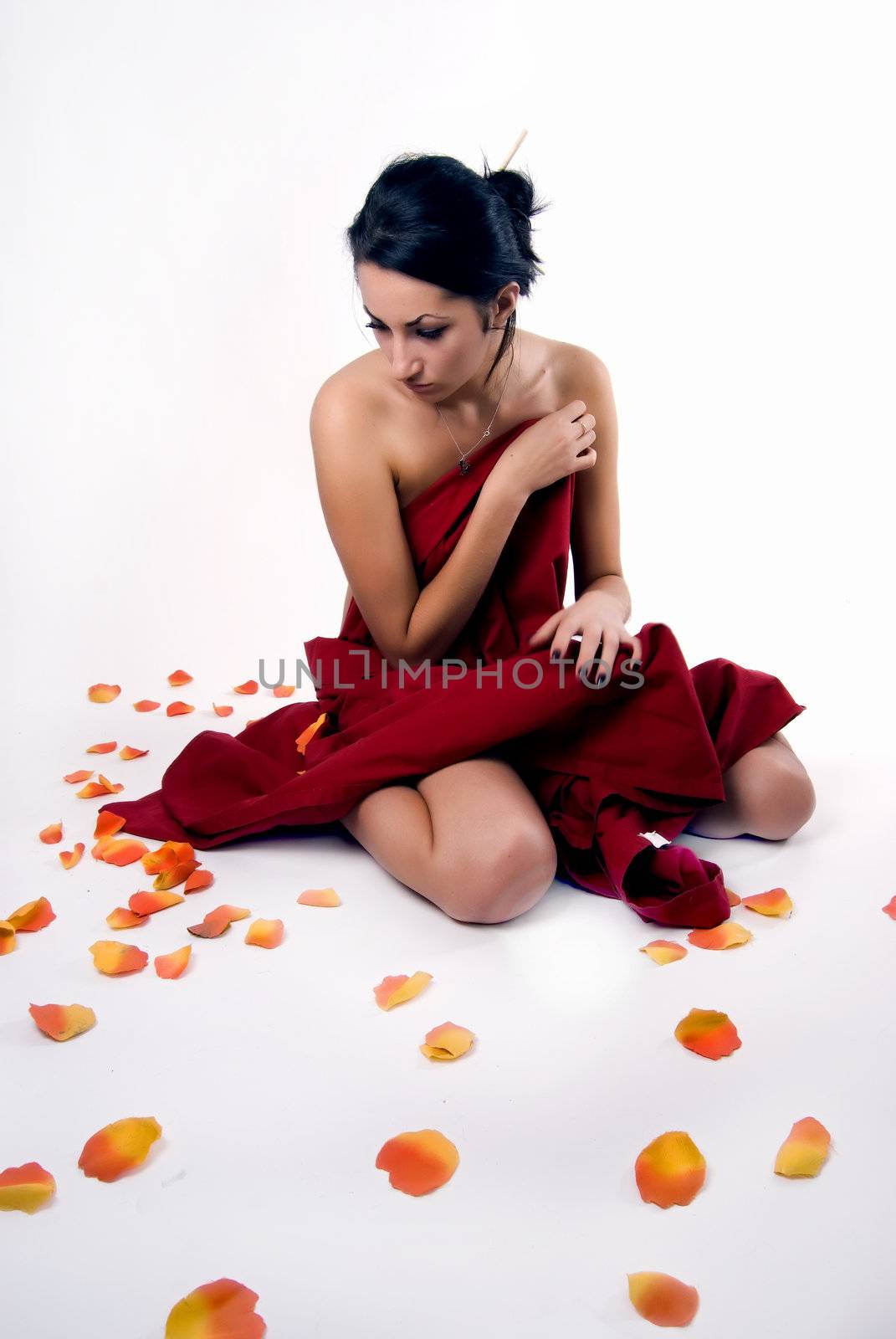 Portrait of a young seductive Asian brunette in falling leaves of roses