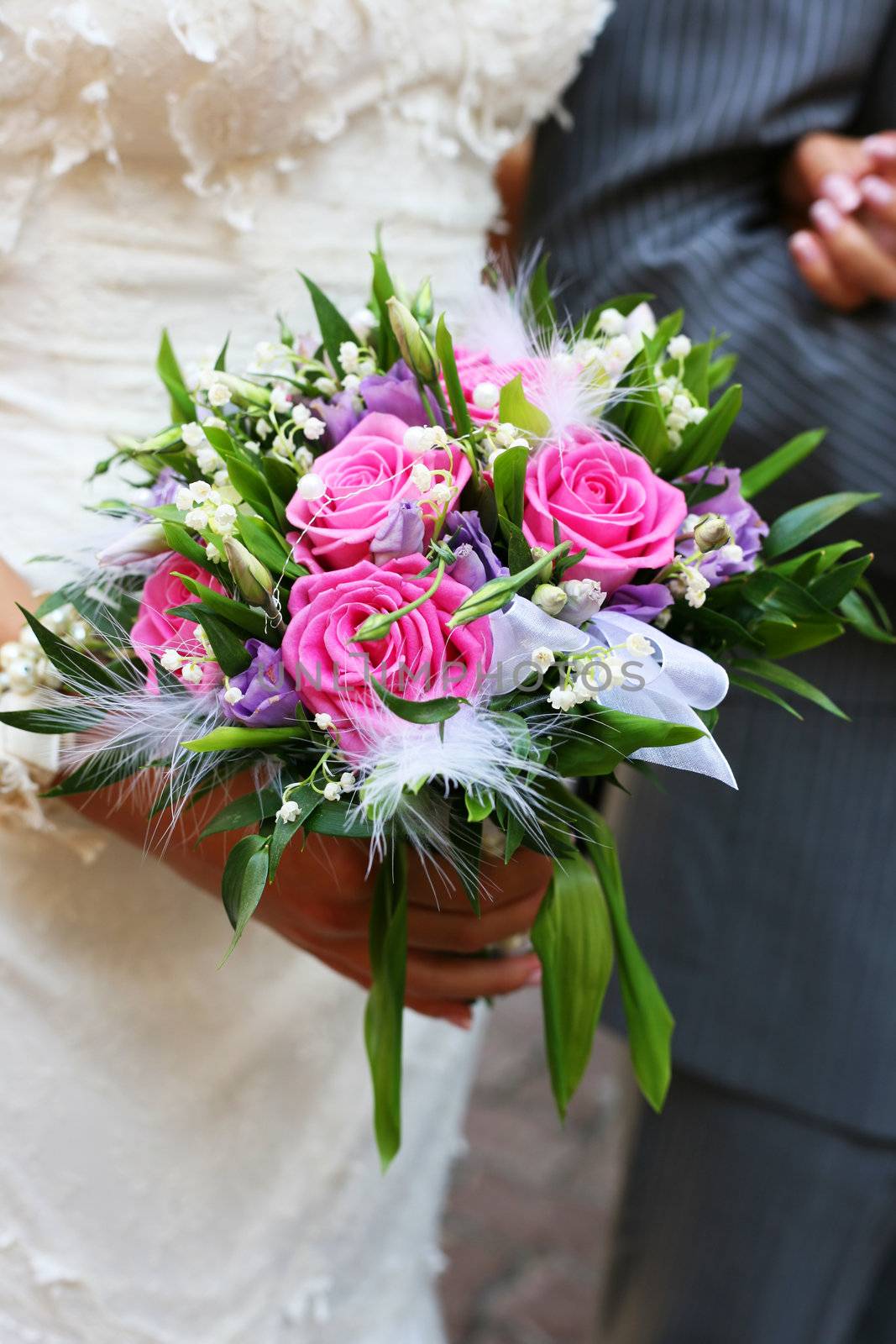 Bouquet of flowers on a background of a dress of the bride and a suit the groom