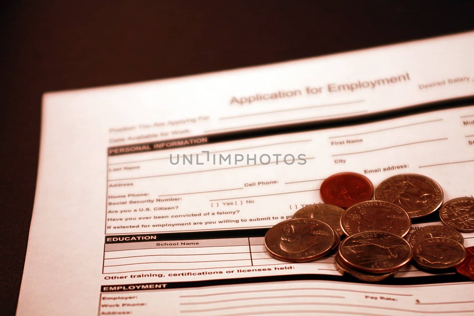 Job application form against black background. Application for employment form with coins in the foreground.