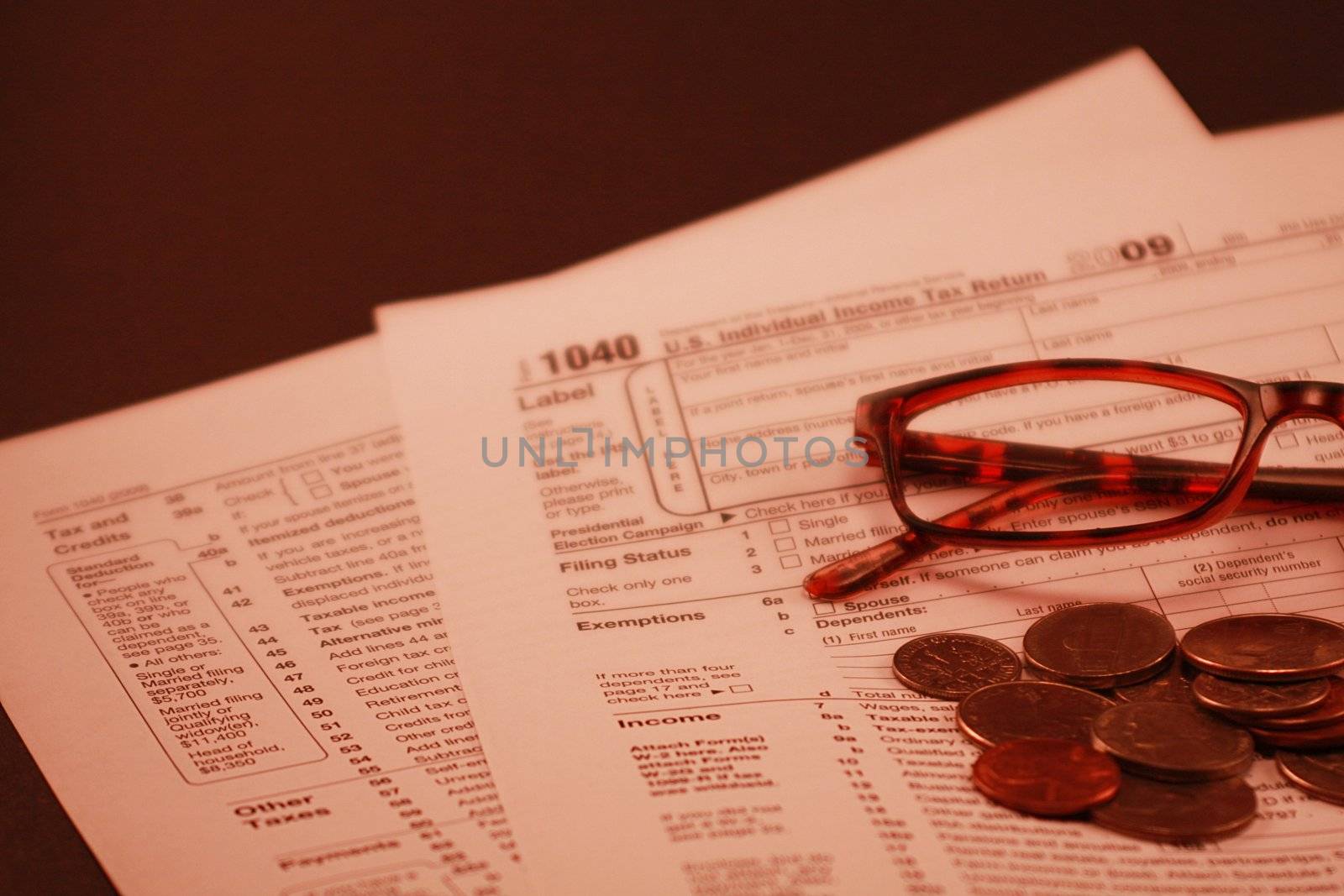 Tax return document Form 1040 end of the year filing. Financial tax documents with glasses and coins in the foreground.