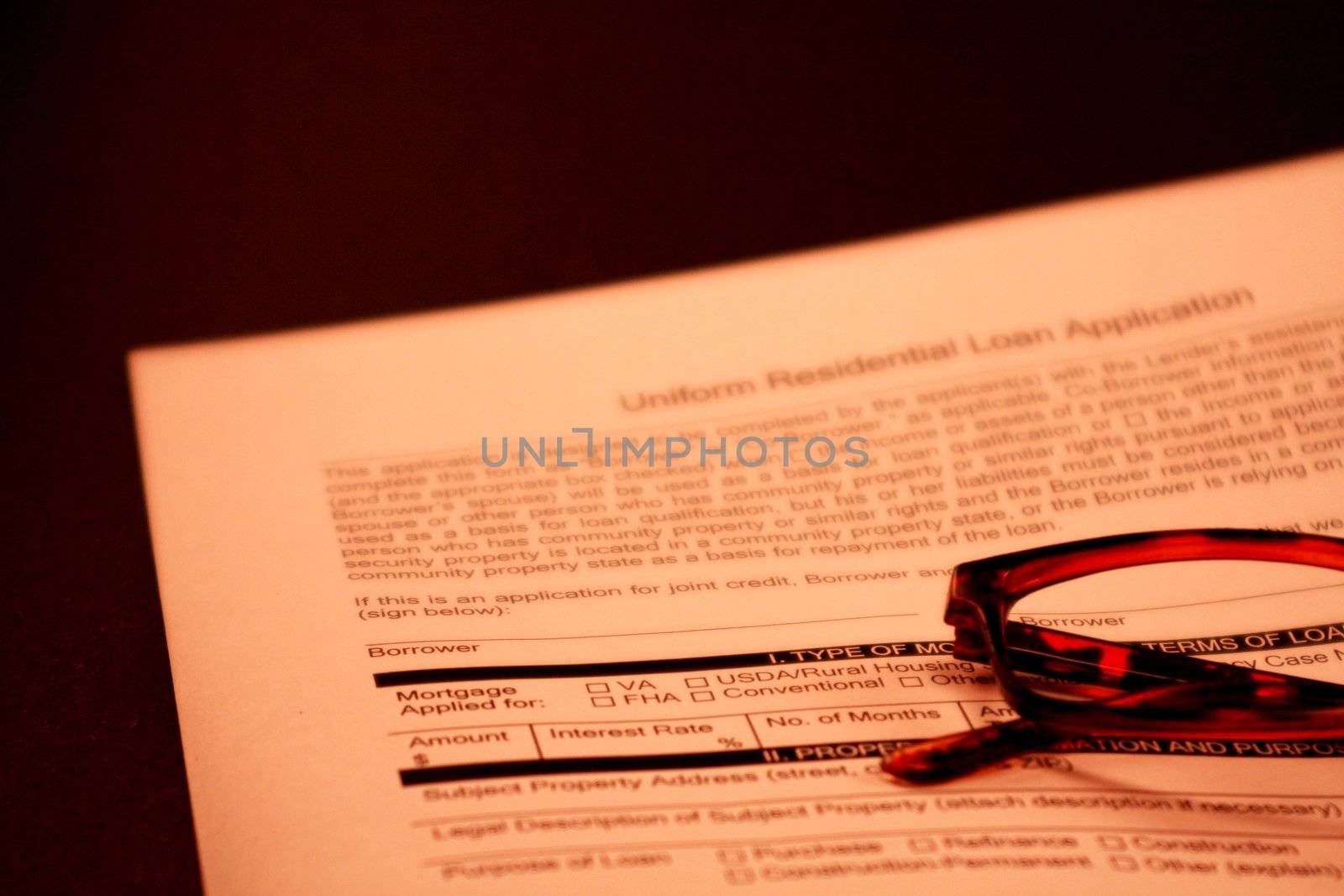 Home loan application against black background. Financial document for mortgage loan with a pair of glasses in the foreground.