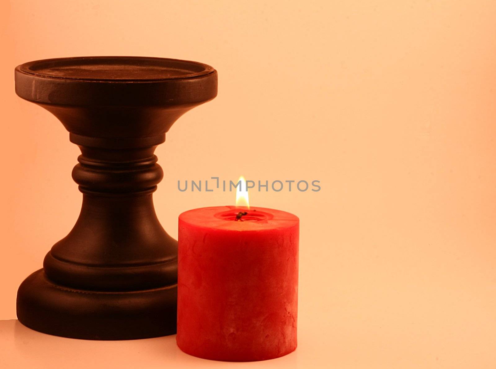 Flaming red candle and black candlestick. Soft illumination for holidays, romance, special occasions and spa