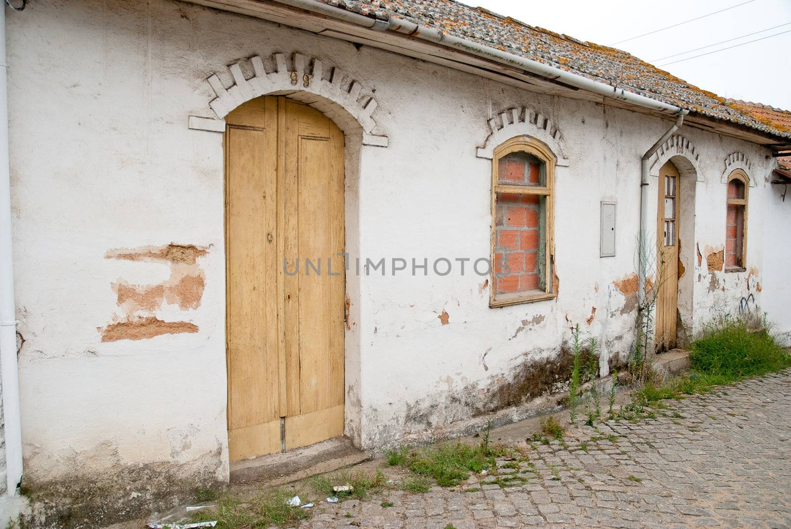 Old house facade with broken door and windows.