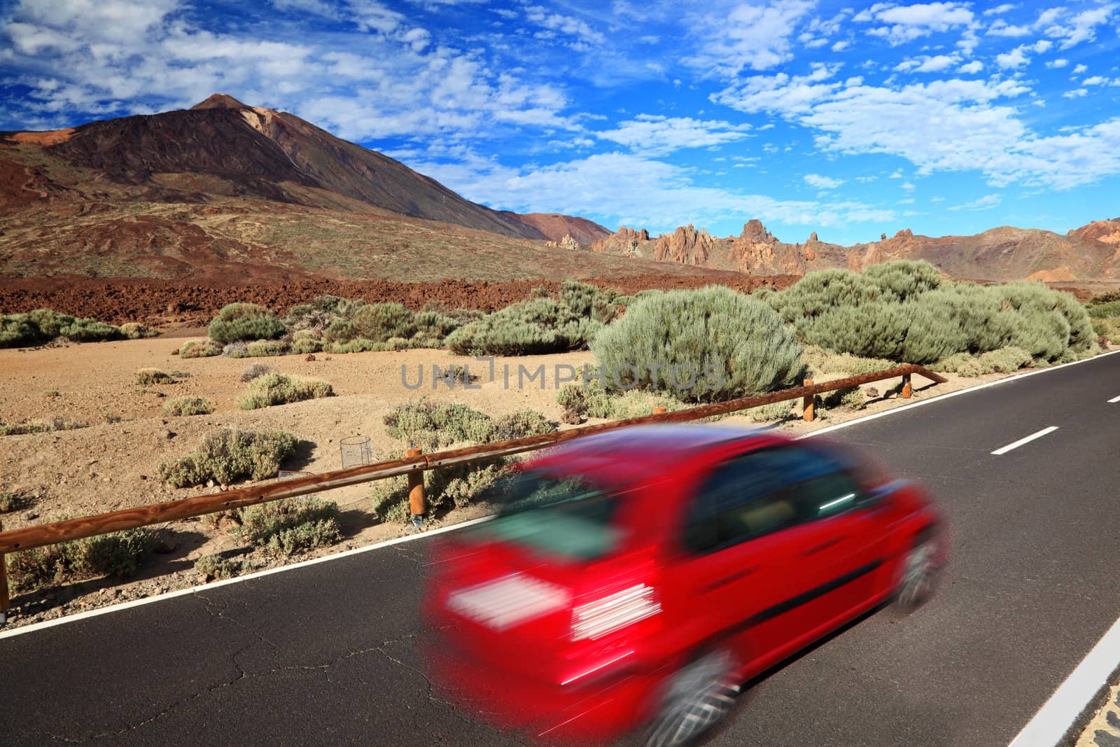 Car in beautiful landscape. Red car road trip image from Tenerife, Canary Islands. Volcano Teide in the background.