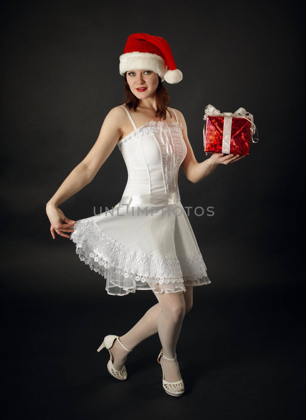 The young woman in a Christmas cap with a celebratory gift