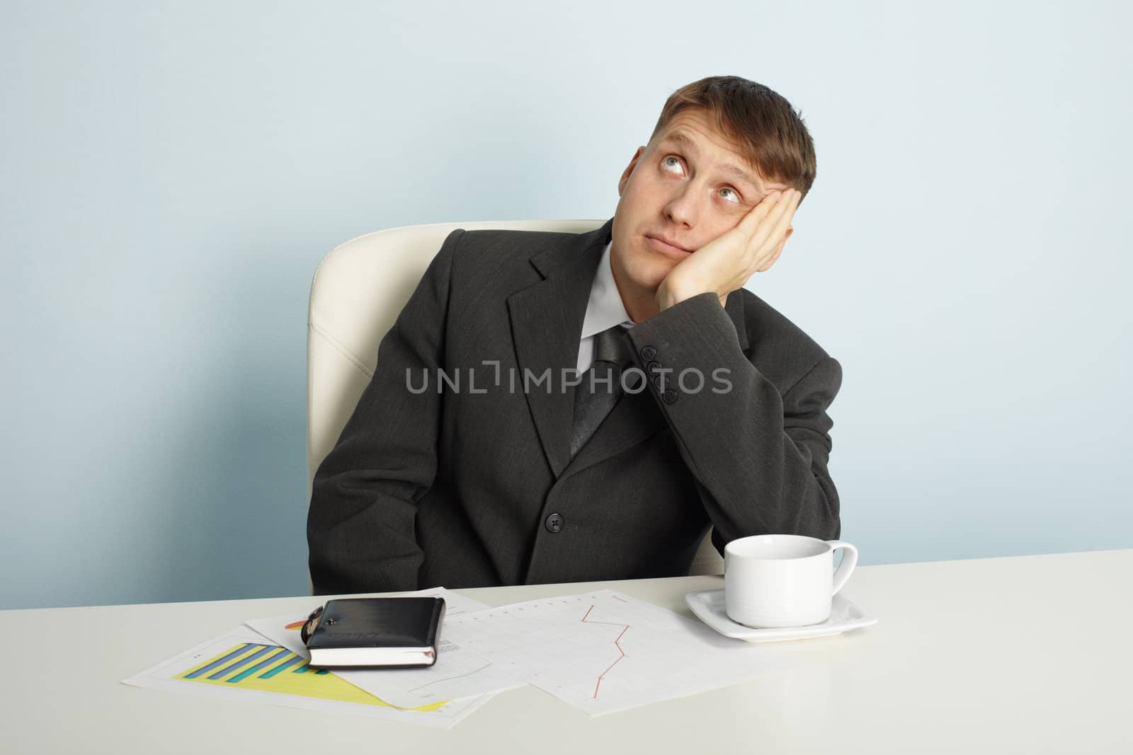 The businessman pensively looks upwards sitting at a table