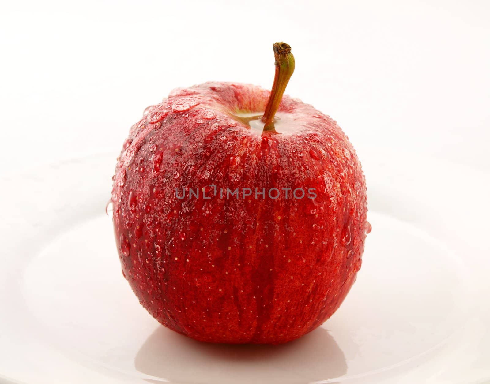 Red apple on white plate, towards white background