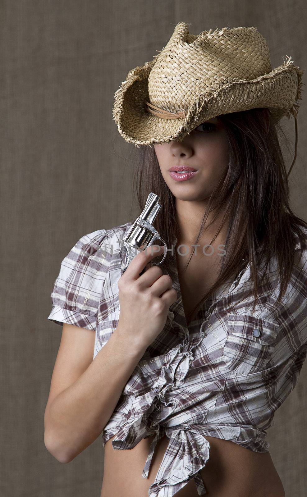 Young brunette cowgirl blowing on a small gun 