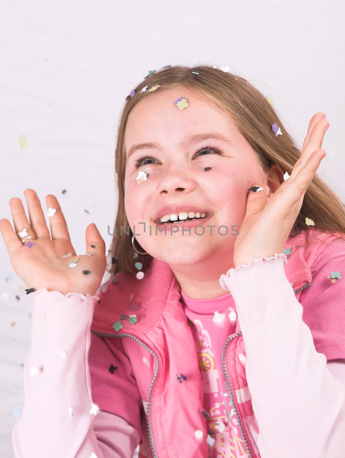 Pretty ten year old girl holding her hands up to catch the confetti coming down