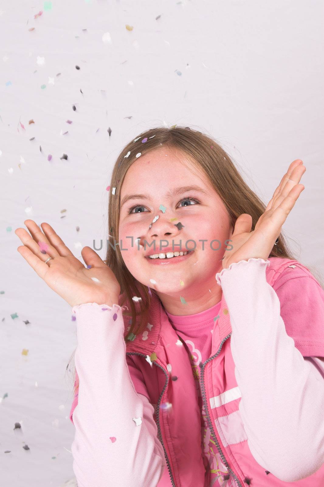 Cute blond girl throwing confetti in the air and watching it come down