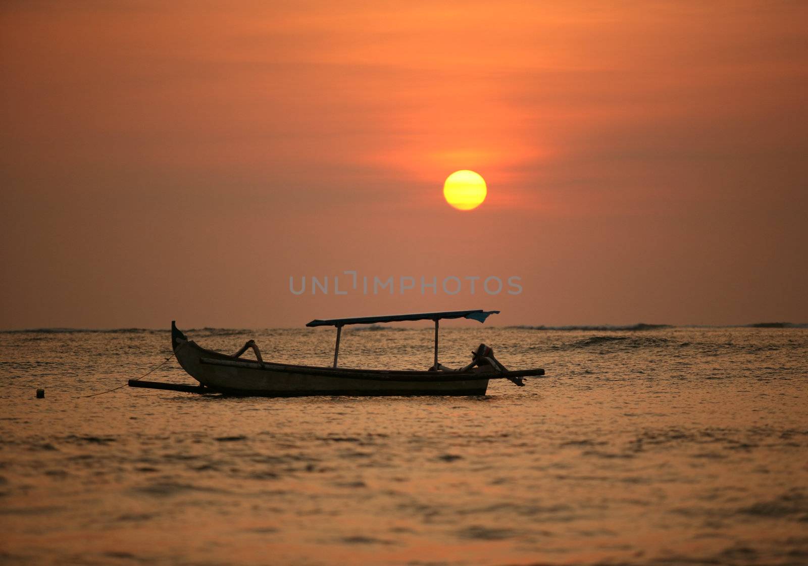 Drifting boat on a sunset. Coast of the Indian ocean. Bali