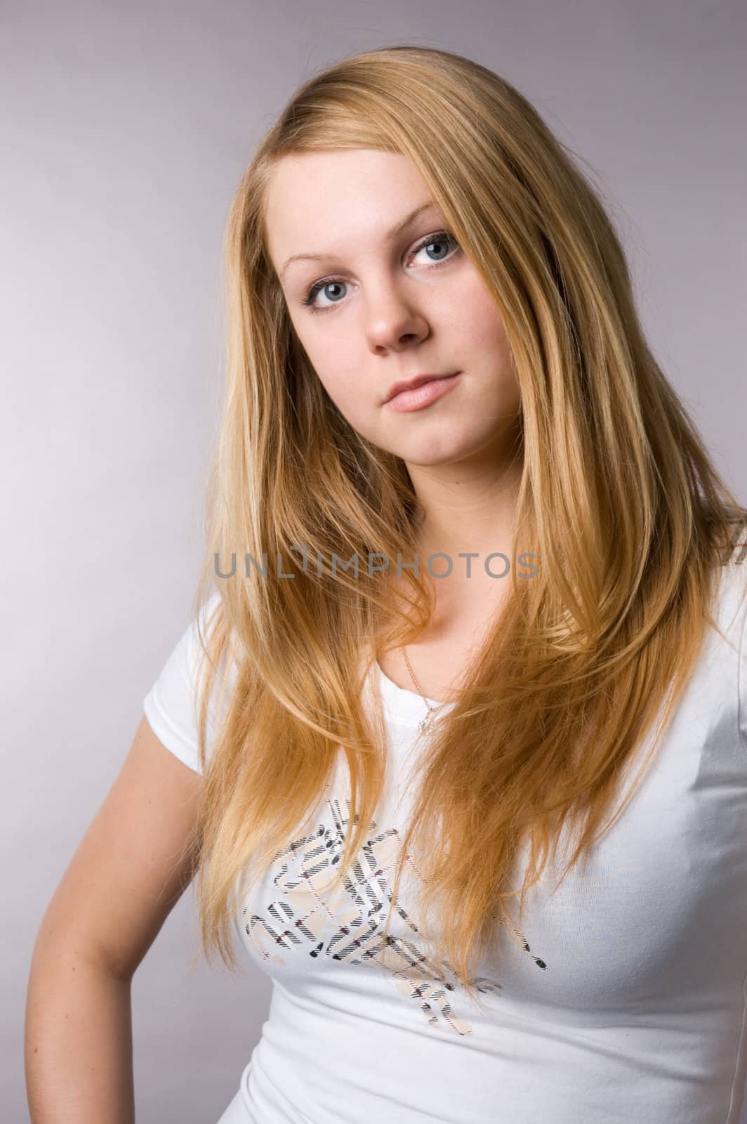 A smiling blonde on a grey background in studio. by andyphoto