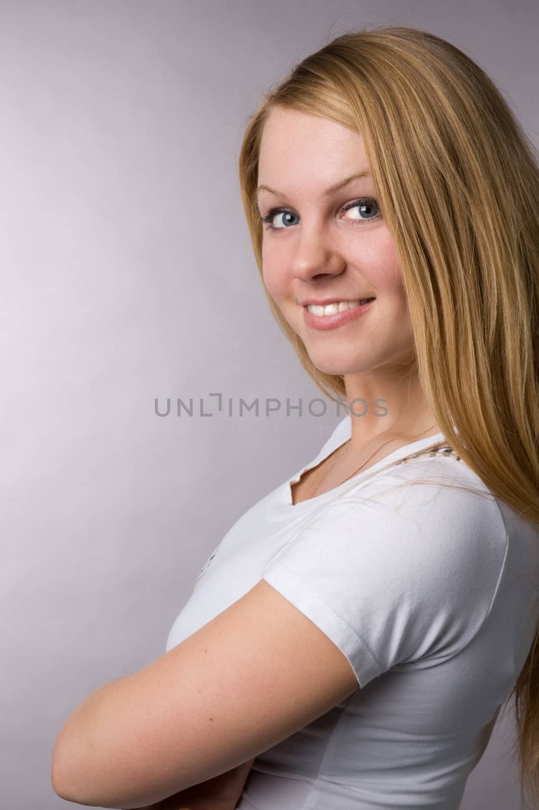 A smiling blonde on a grey background in studio. by andyphoto