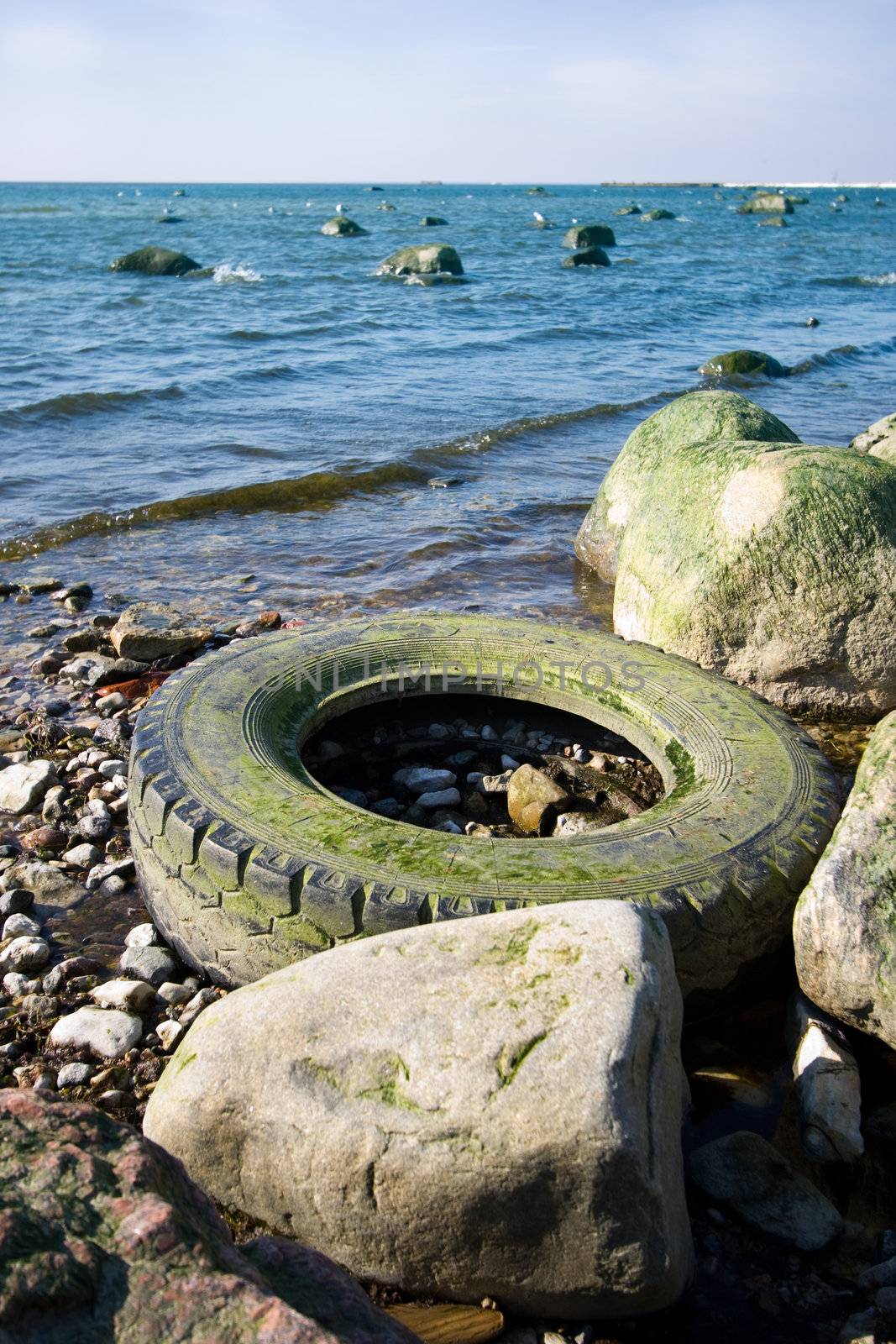 Old tyre polluting a seashore due to insufficient recycling