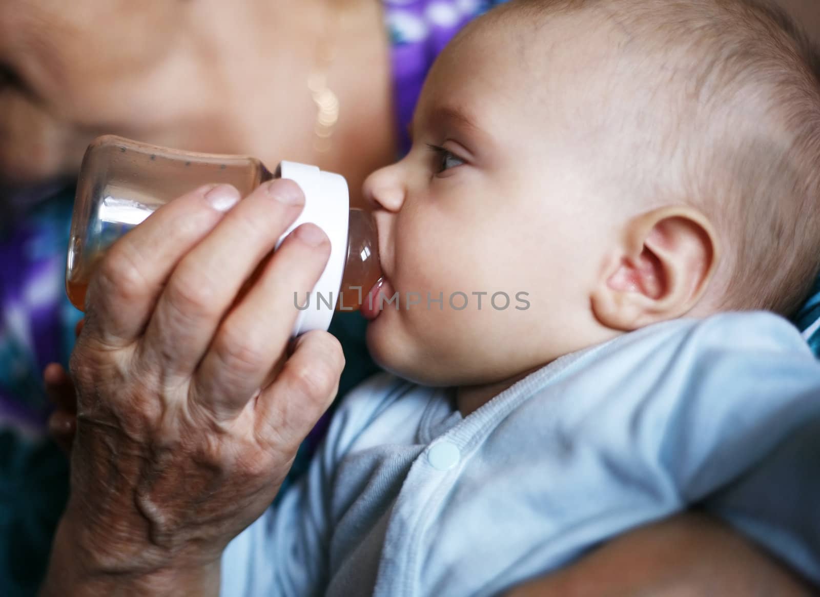 The grandmother feeds from a bottle with tea of the grandson
