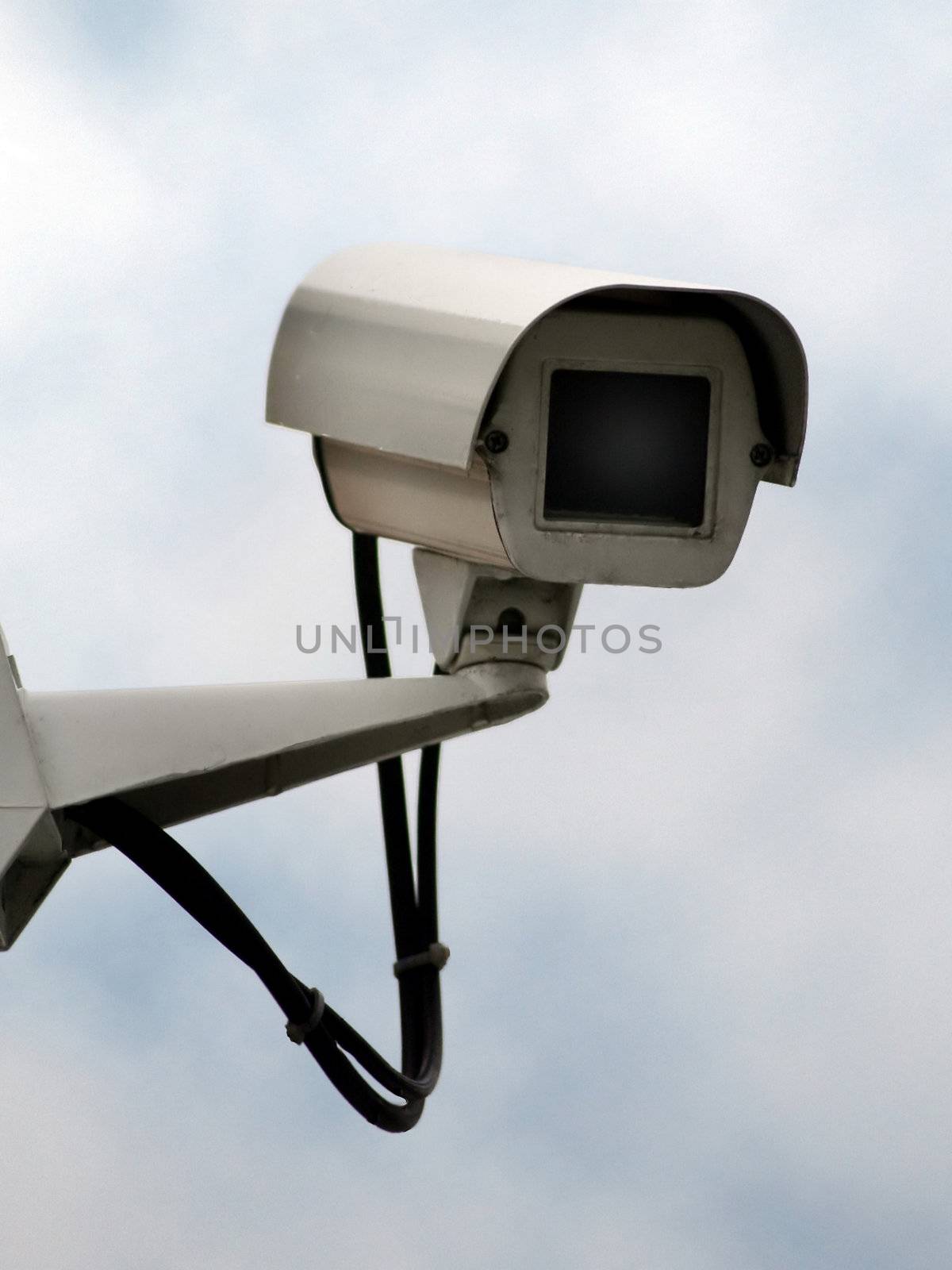 Cctv security camera on a blue sky background- deliberately stark image