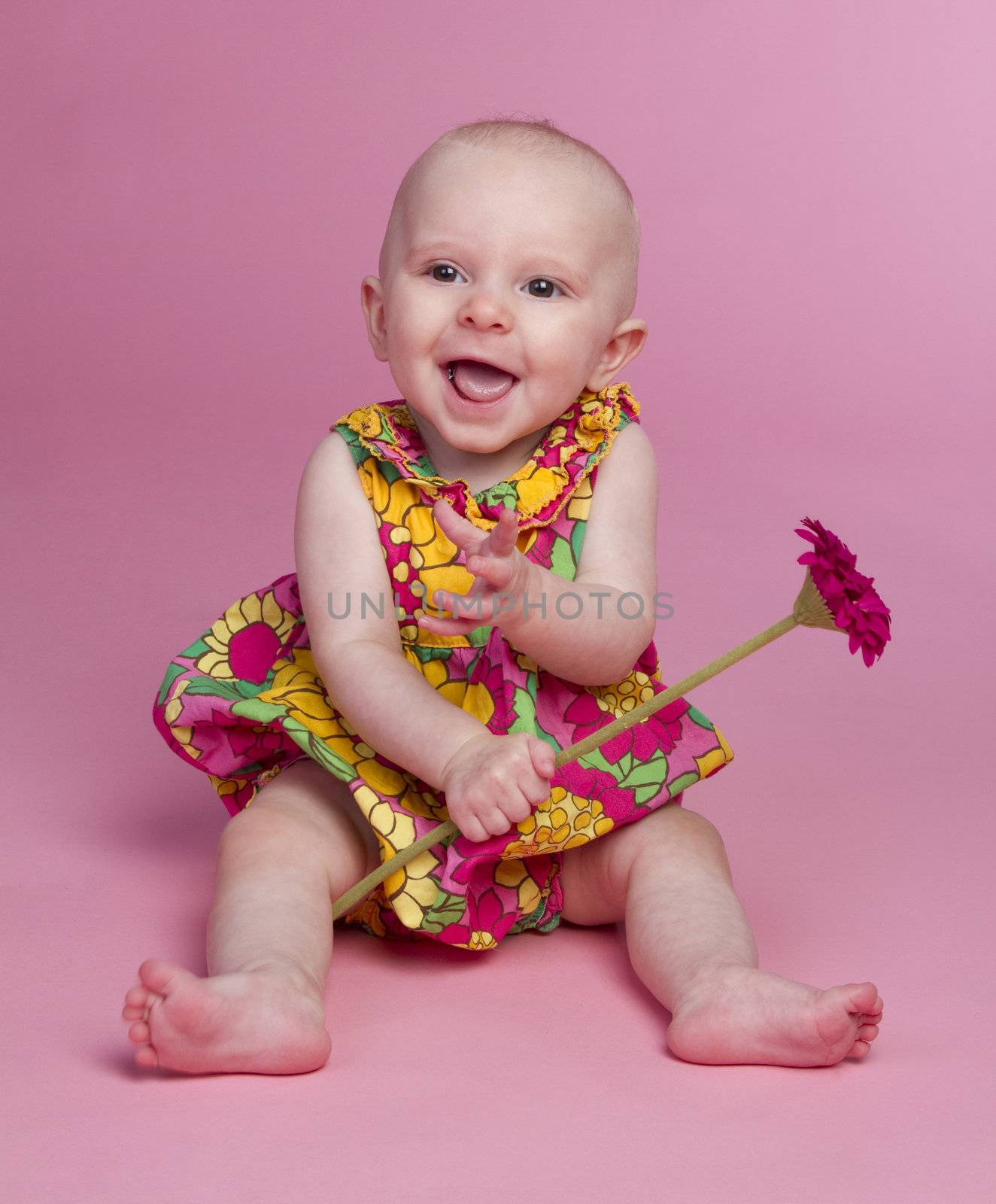 Smiling baby girl holding flower