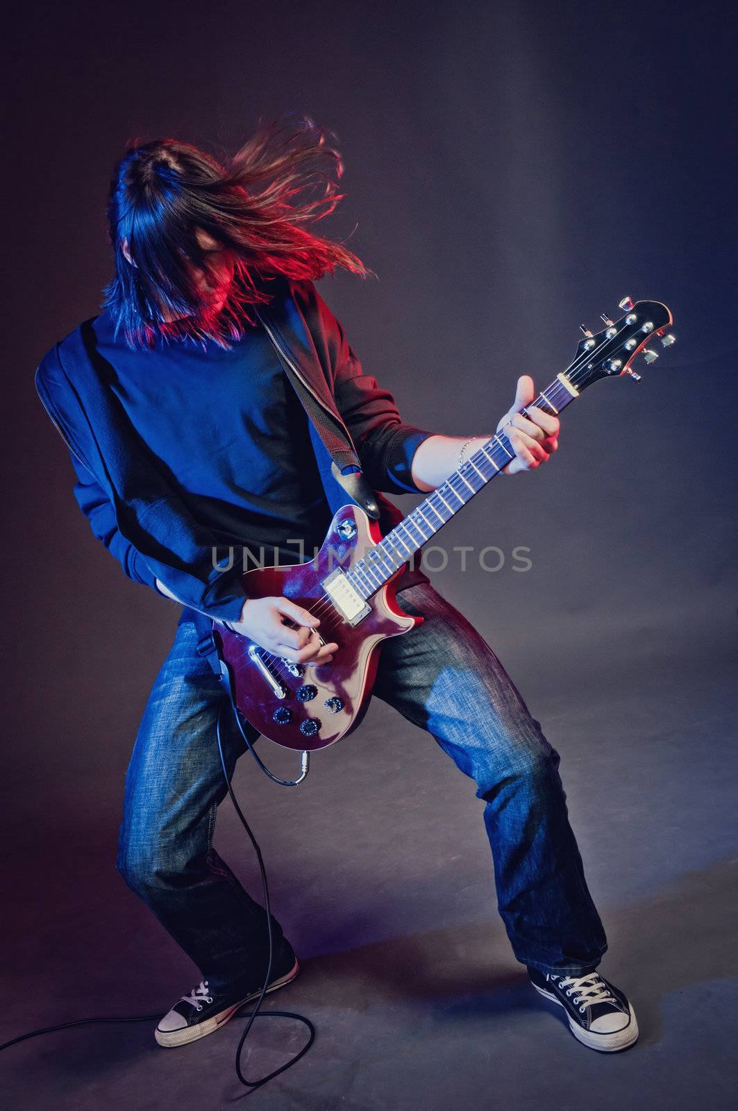 Rock-star perfoming loud music on red electric guitar