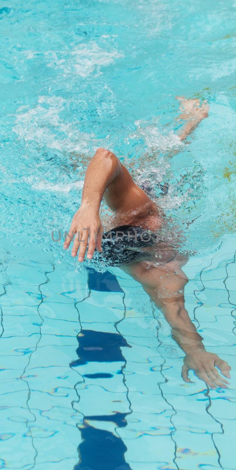 Young male athlete swimming freestyle in a swimming pool