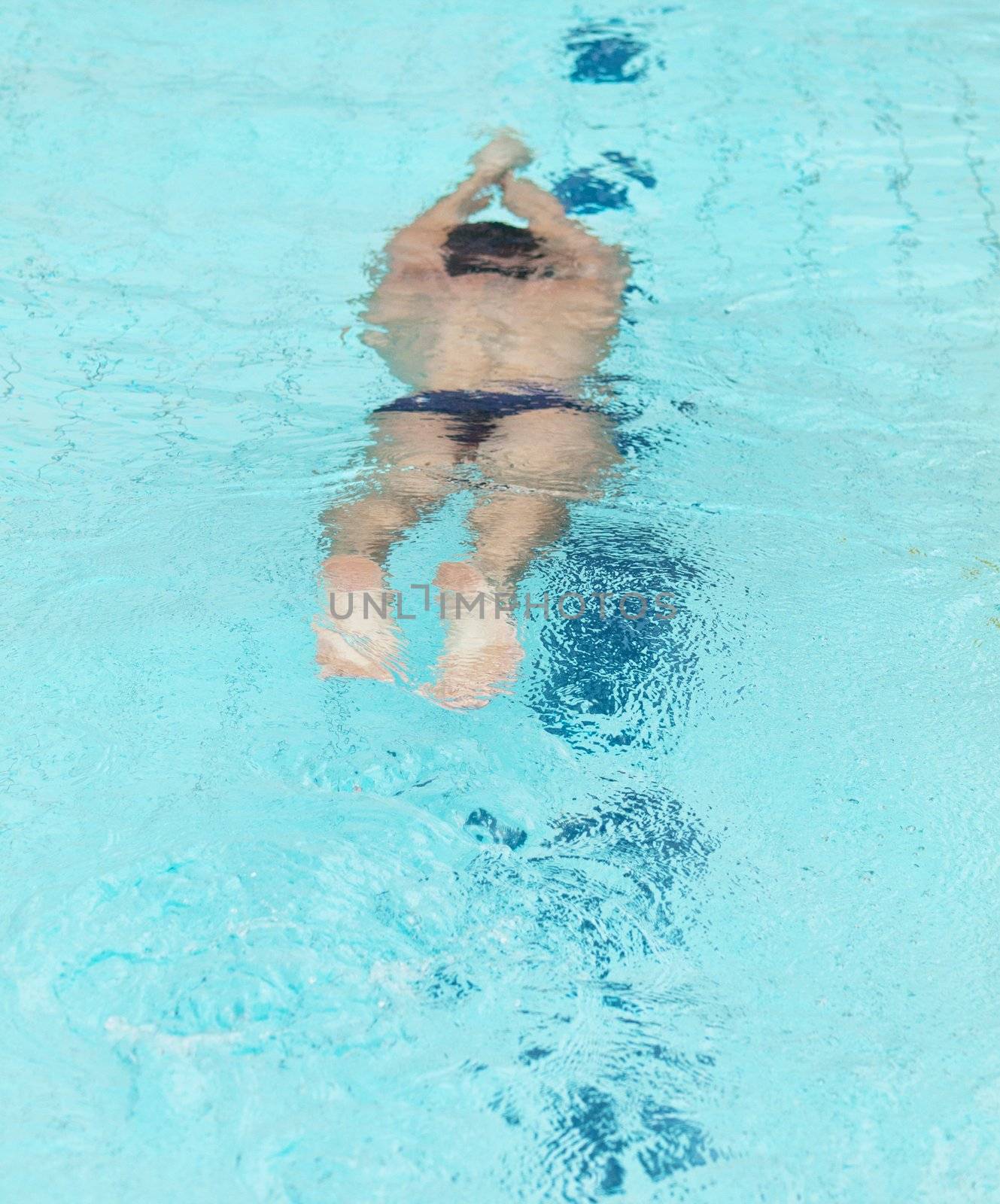 Young male athlete swimming underwater in a swimming pool