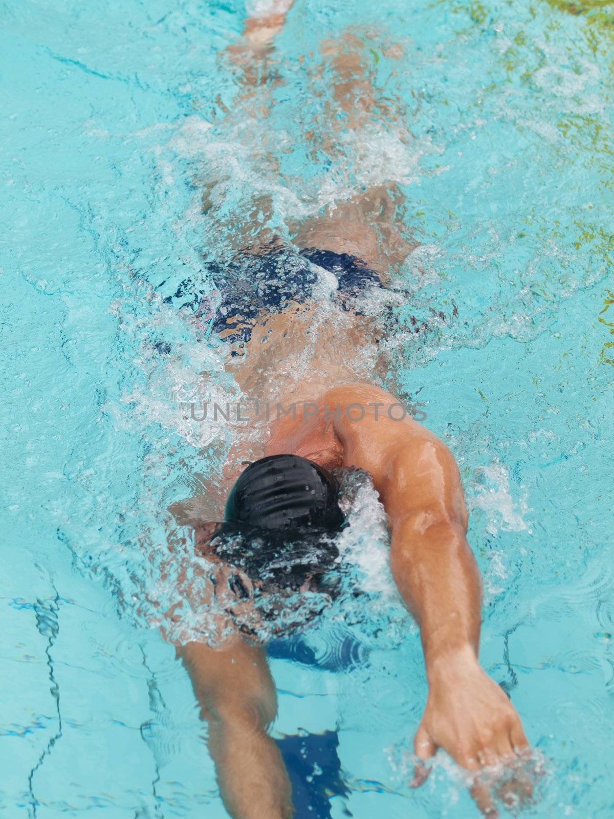 Young male athlete swimming freestyle in a swimming pool