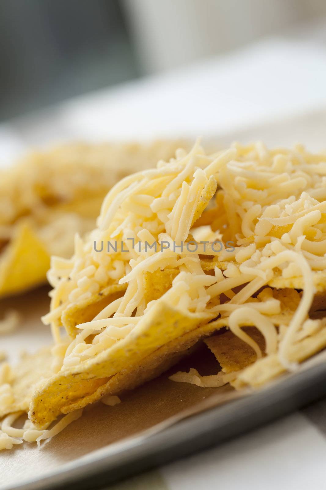 Nacho chips with grated cheese ready for the oven.