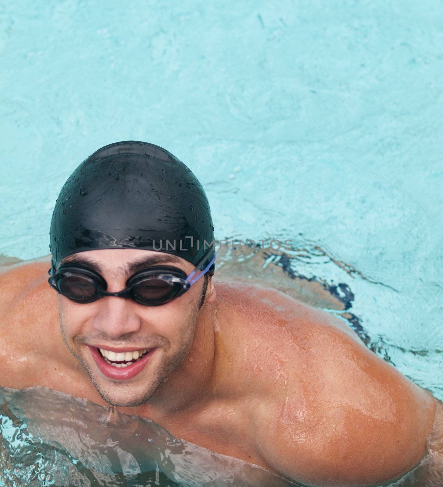 Male swimmer wearing cap and googles smiling