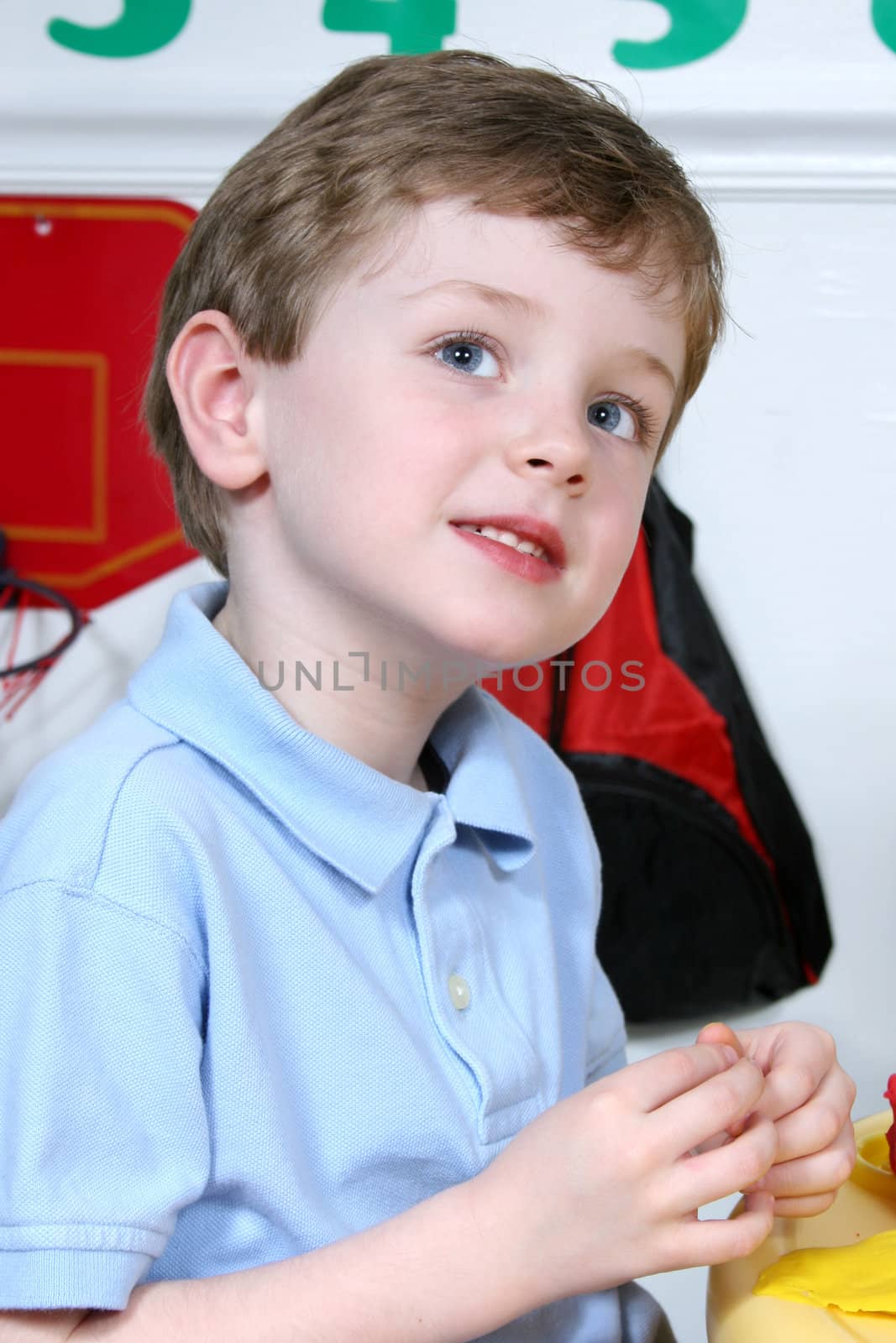 Handsome and happy little boy sitting in a pre-school playing with colored dough.  Shot with the Canon 20D.