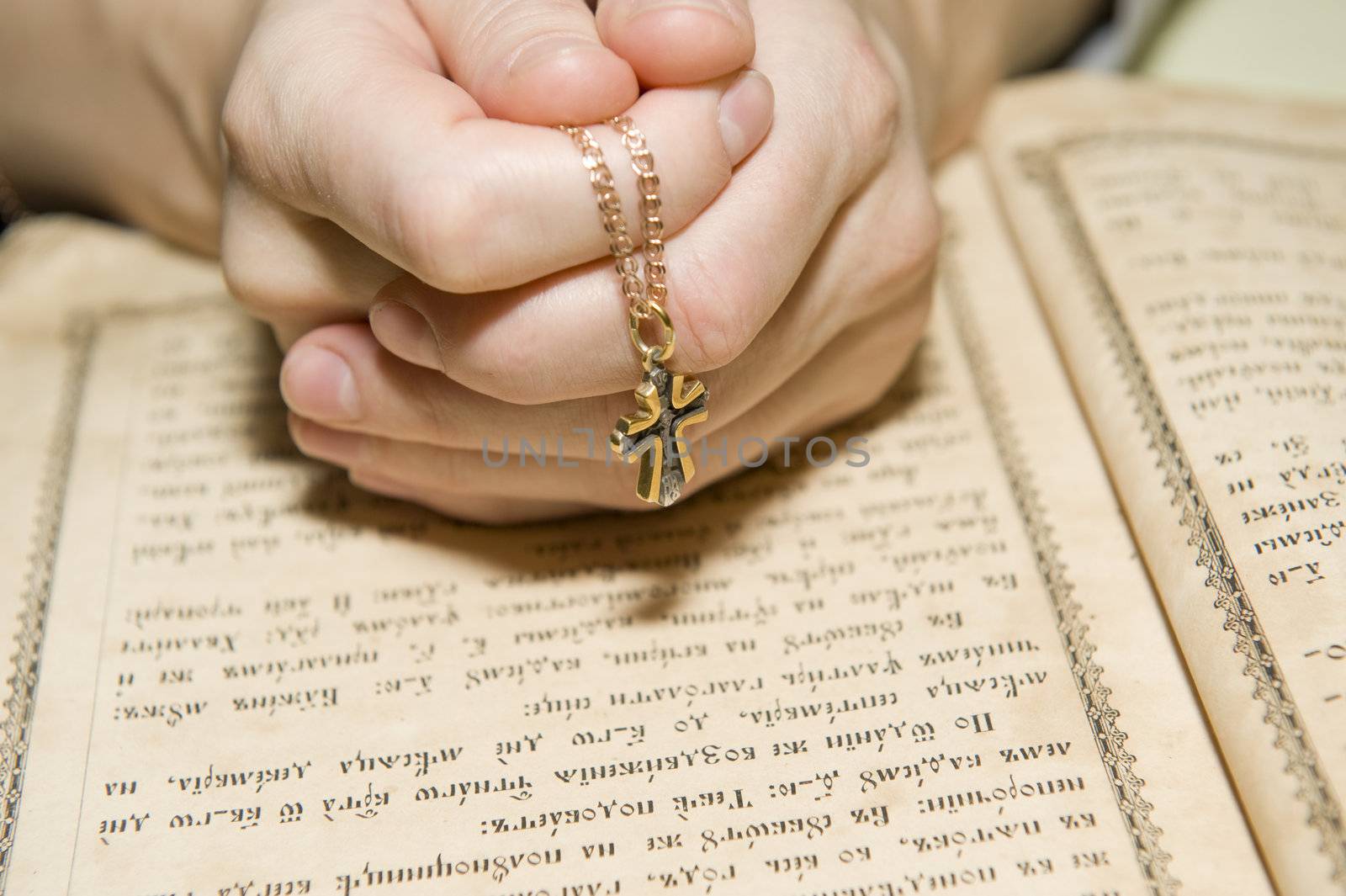 Female hands during reading of a prayer against the orthodox bible 