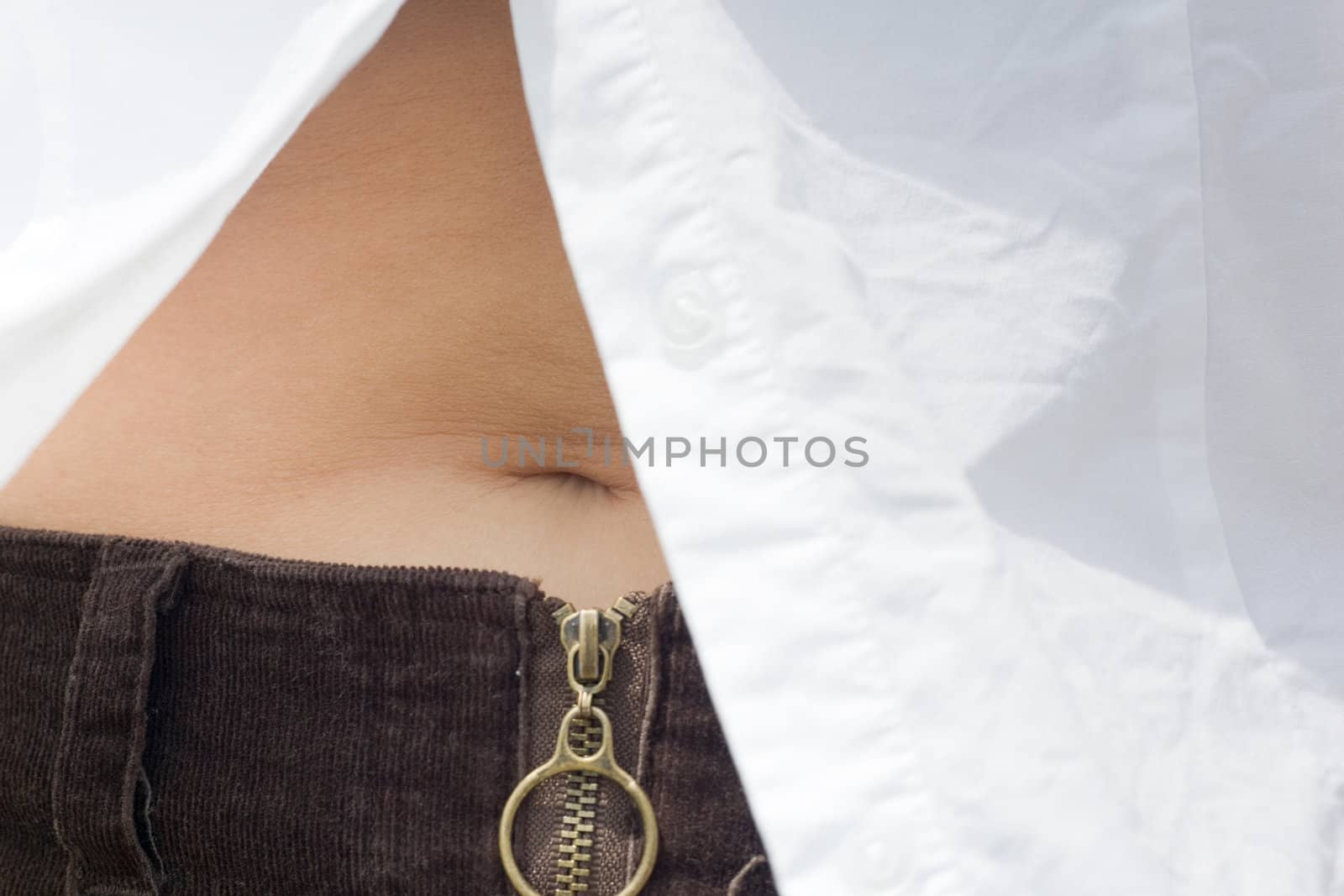 Closeup of a woman's mid-section, revealed by an unbuttoned white shirt, showing the belly button.