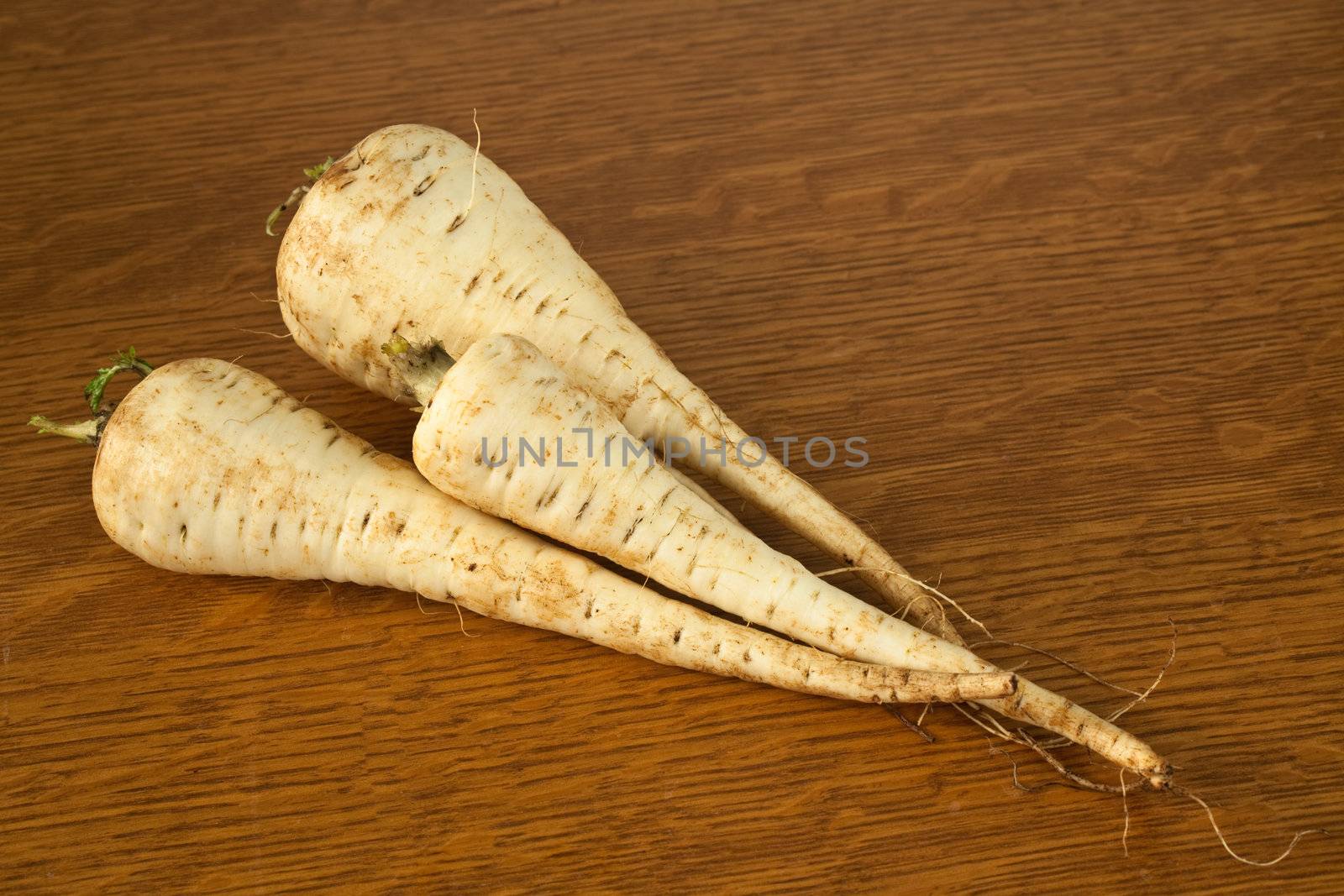 Three parsnips on a table ready to be prepared for a meal