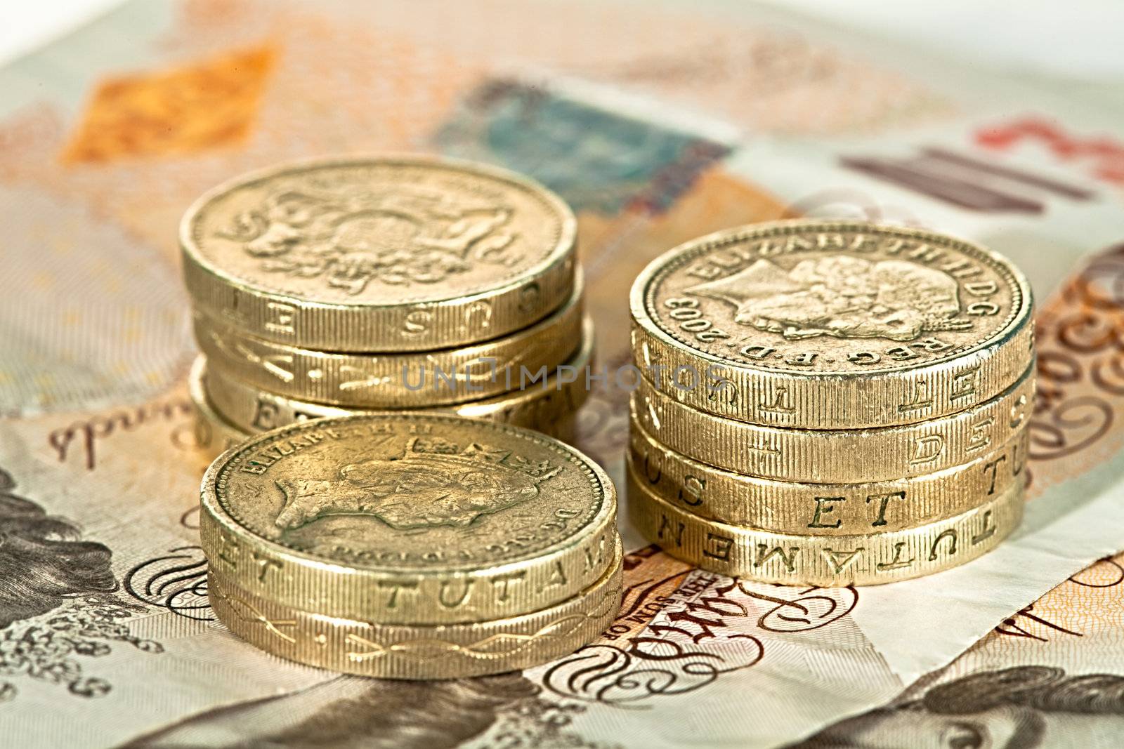 A pile of British pound coins on ten pound notes
