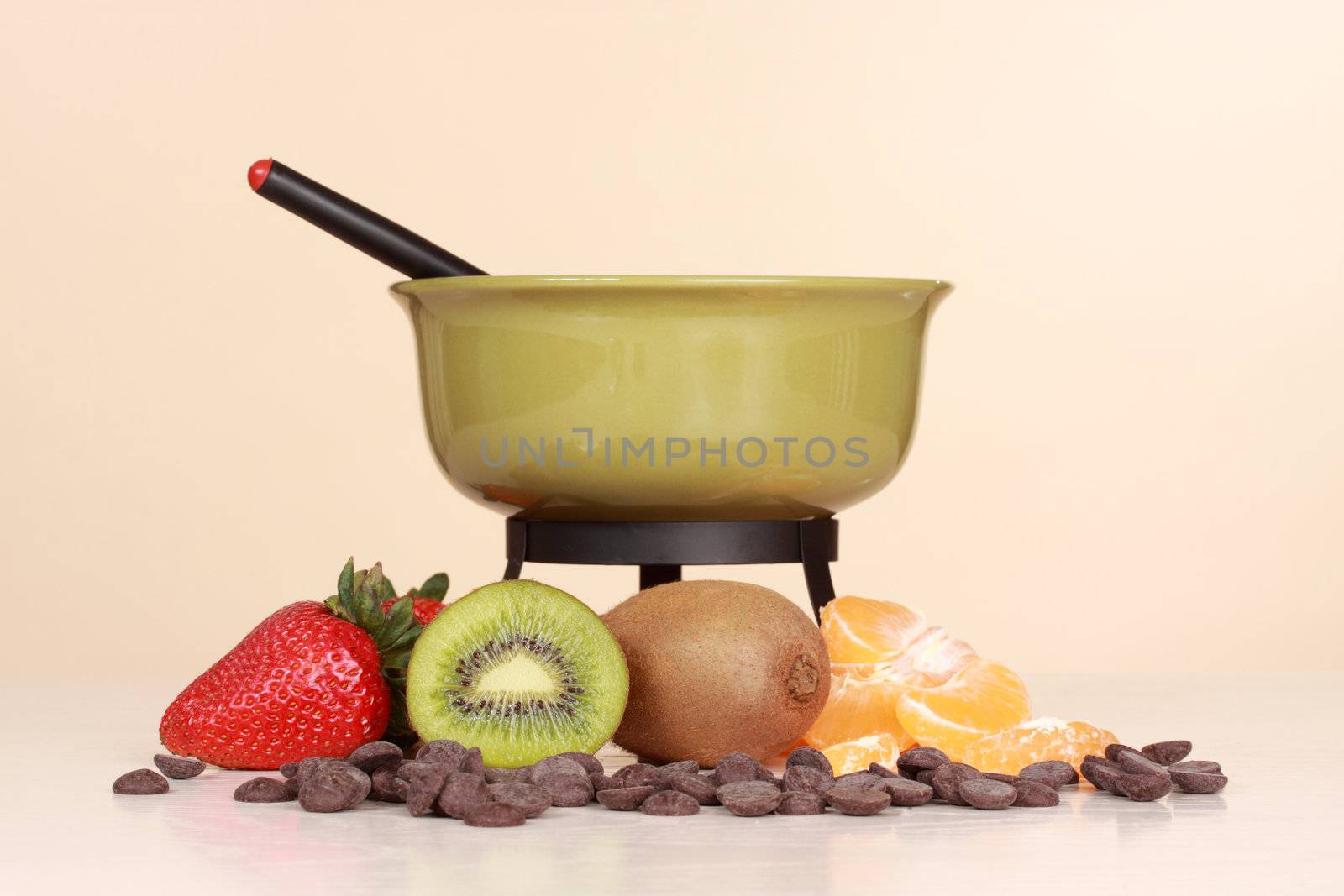 chocolate fondue kit and fresh fruit, beige background