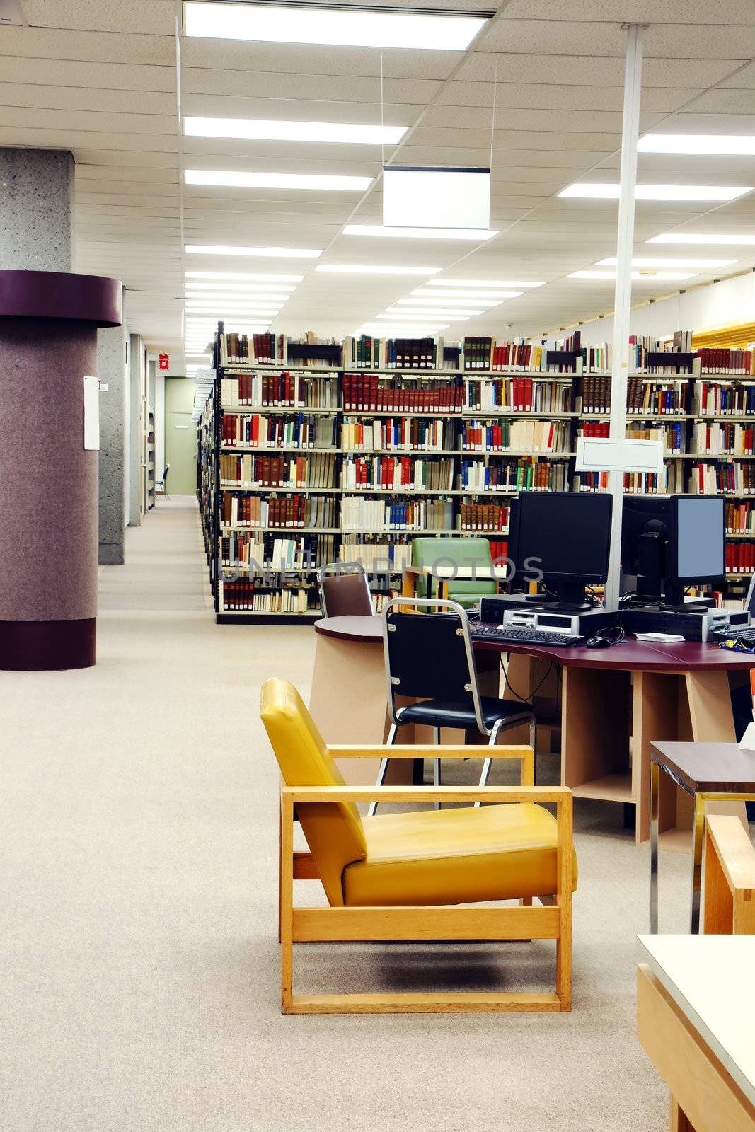 University library with comfortable leather reading chairs and computer station for research, copy space on the left.