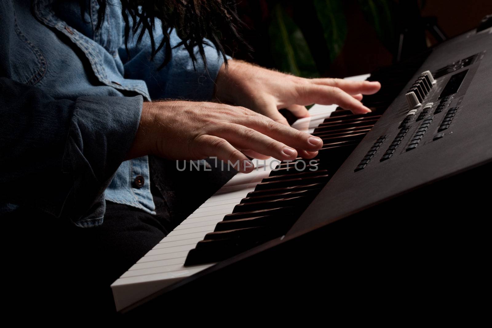 Male Pianist Performs on the Piano Keyboard with Dramatic Lighting.