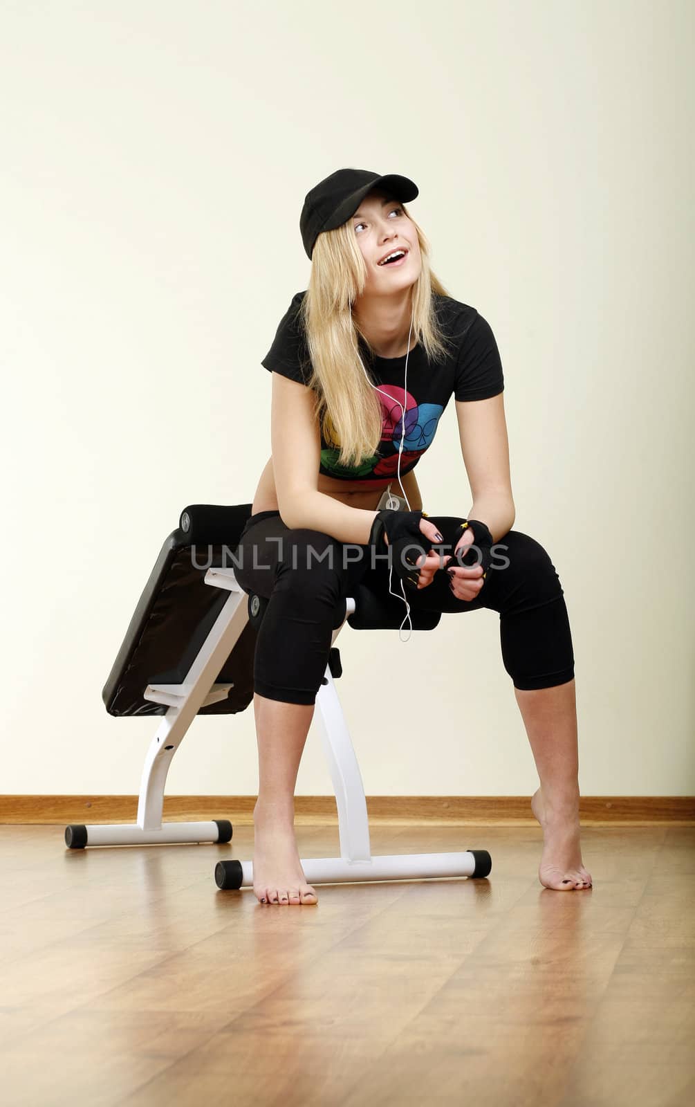 smiling girl in cap sitting on fitness machine