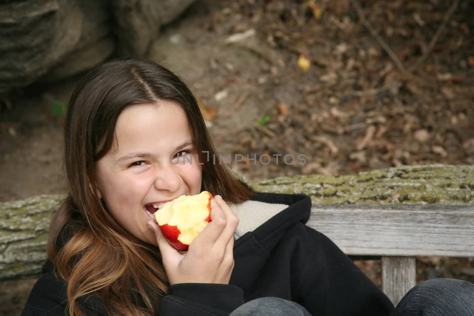 Young girl on park bench eating a delicious and healthy apple