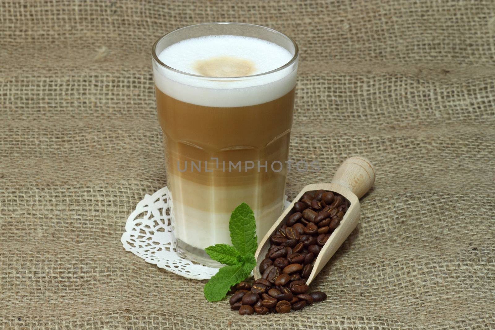 Latte Macchiato in glass with coffee grain on brown background
