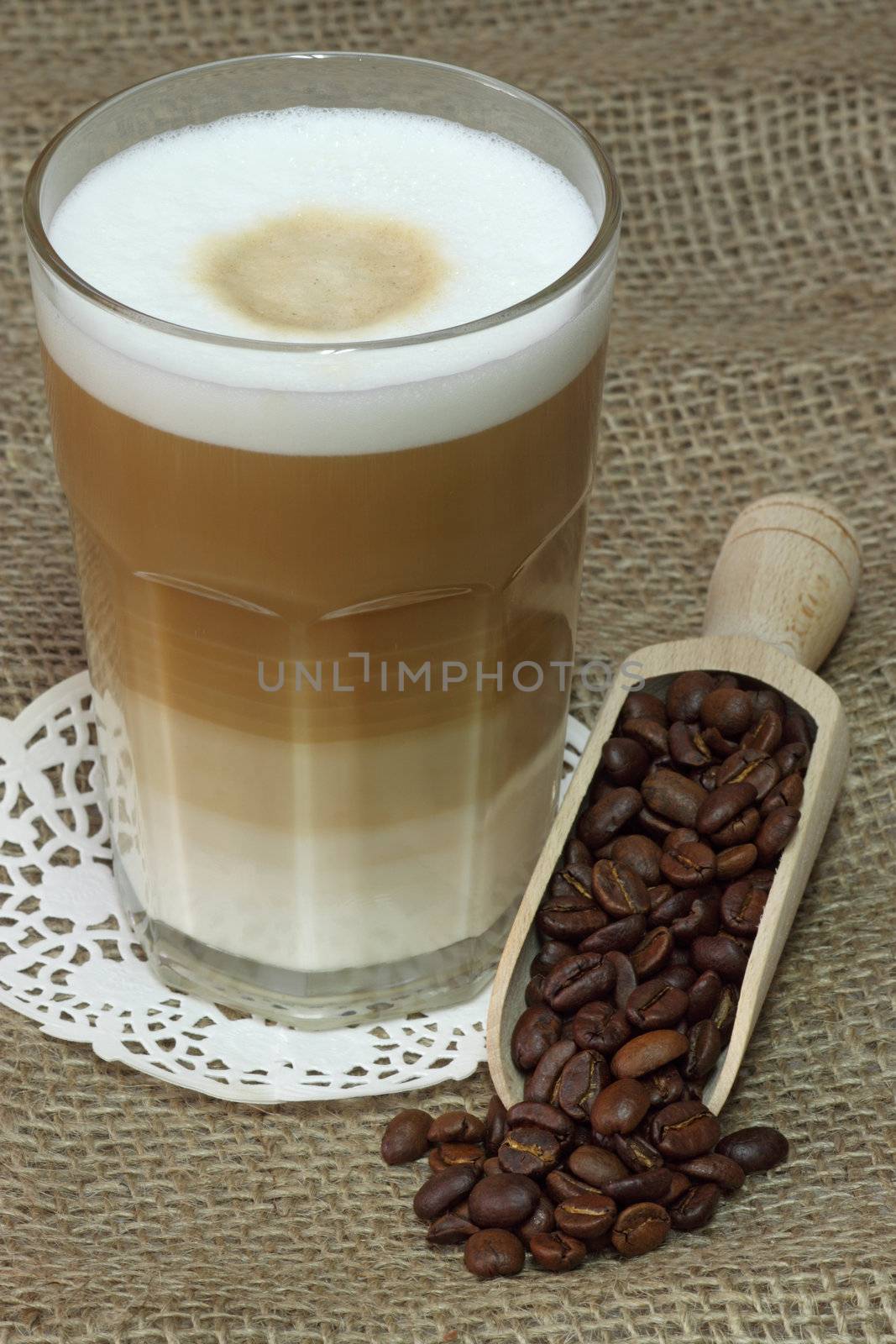 Latte Macchiato in glass with coffee grain on brown background