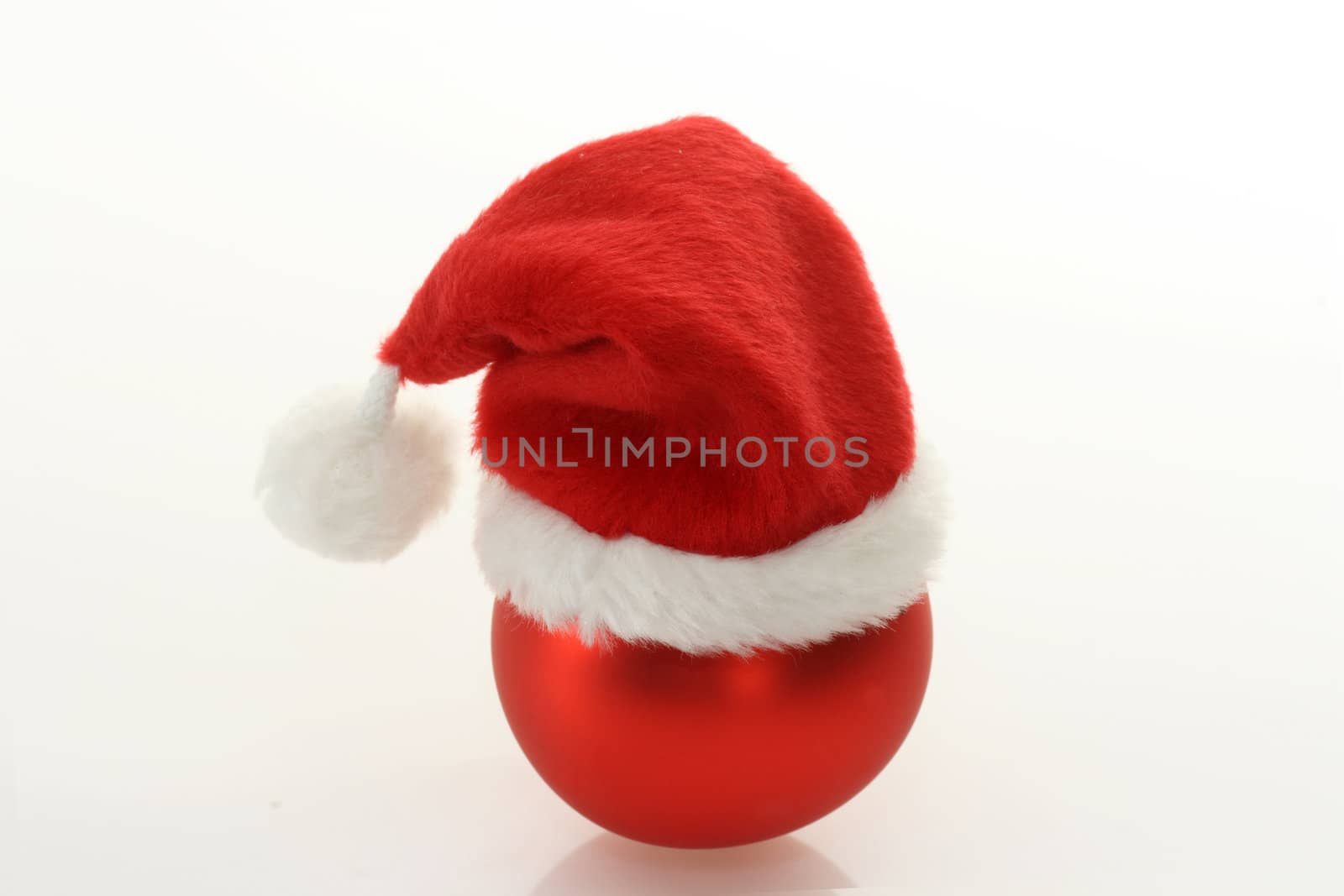 Christmas ball with santa claus cap on bright background. Shot in studio.