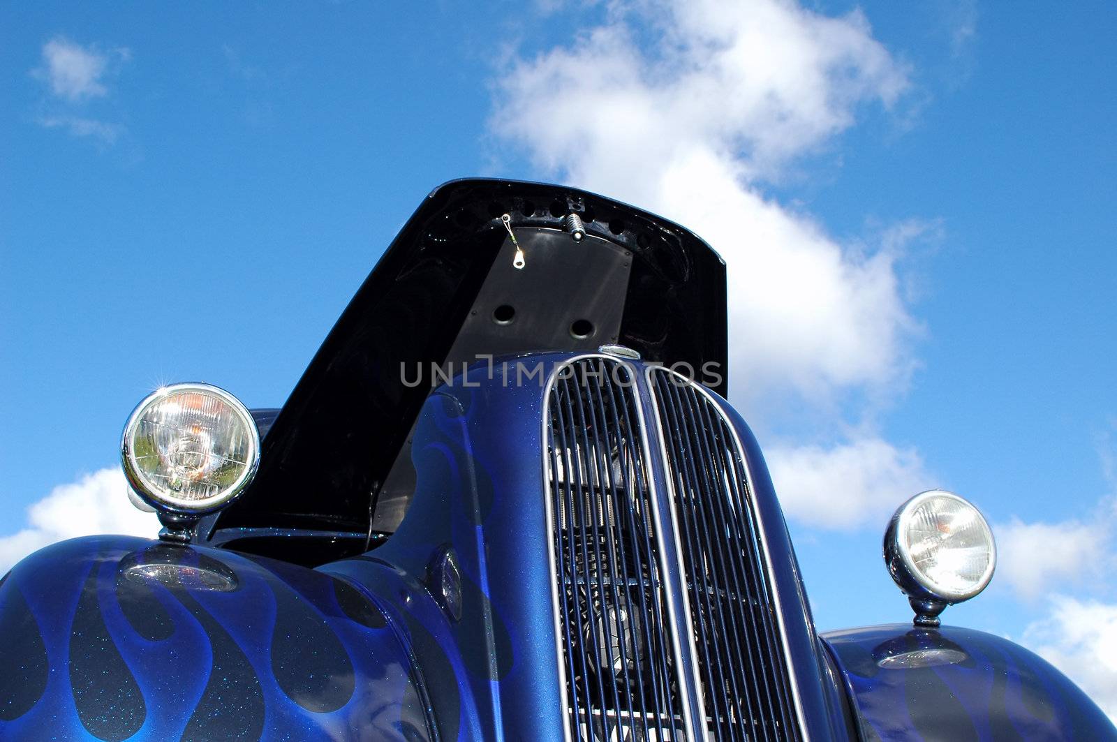 metallic blue hot rod against cloudy sky