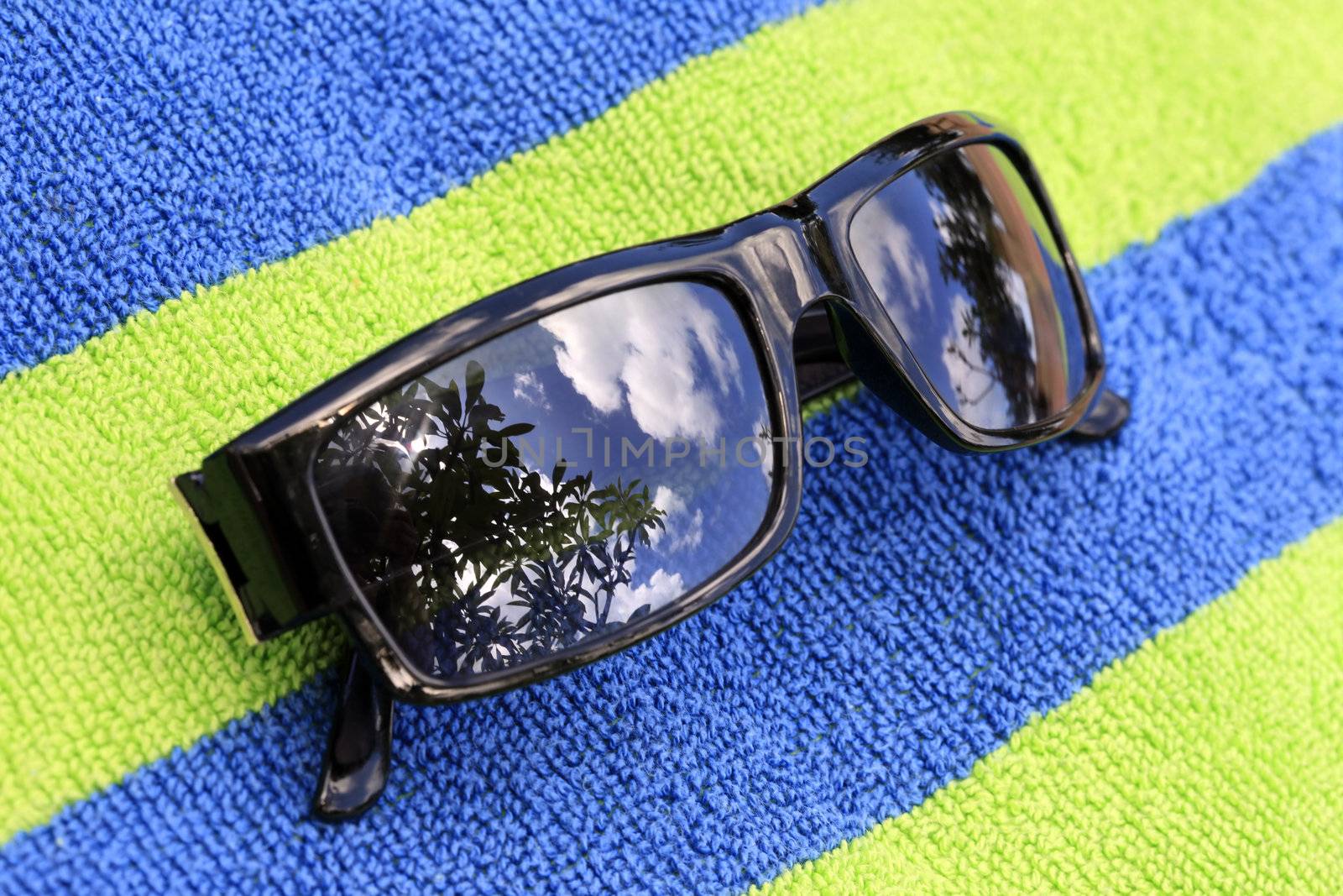 Solar glasses with reflection on a blue-green towel