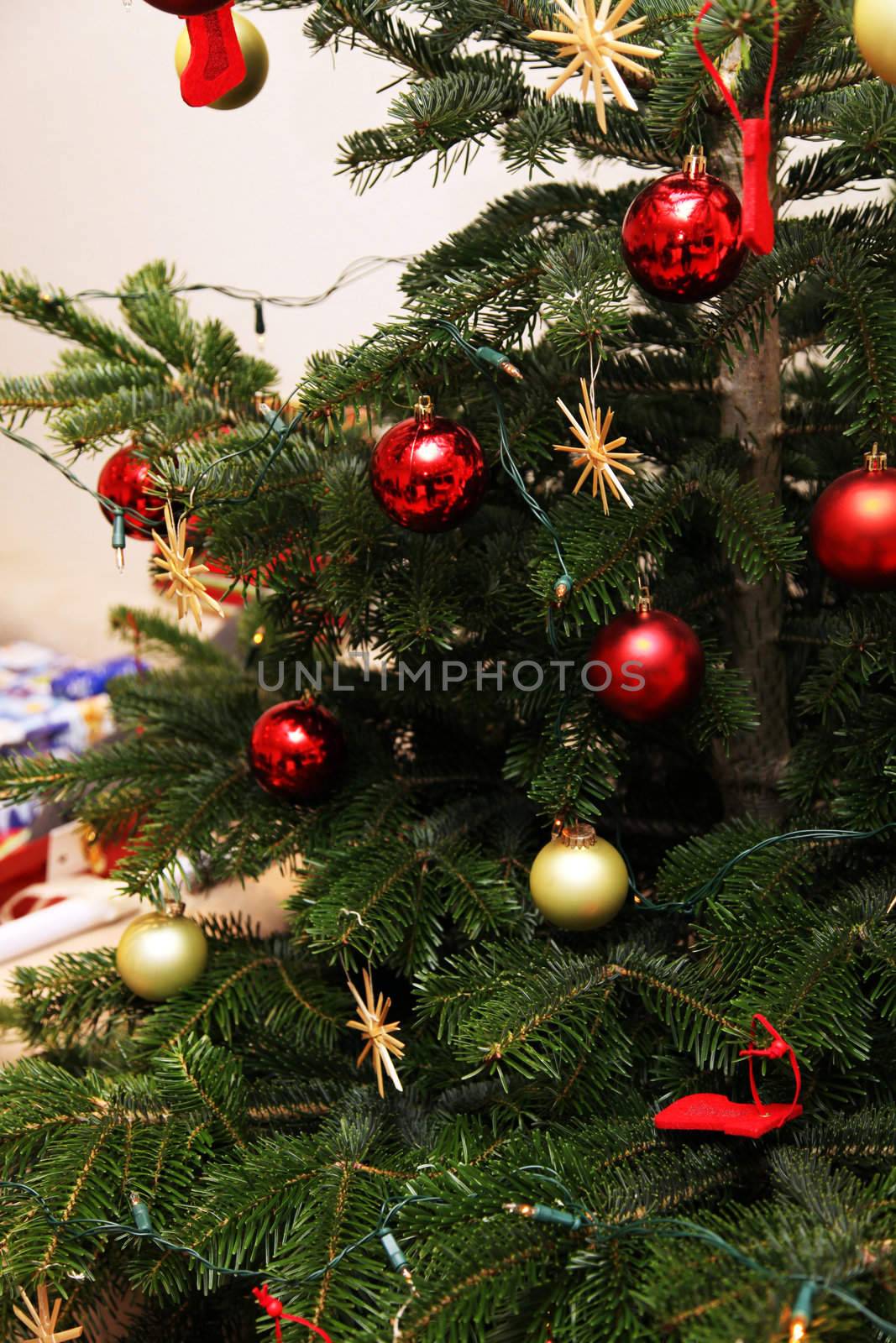 Christmas tree decorated with red and gold Christmas ball. Under the tree are many Christmas gifts
